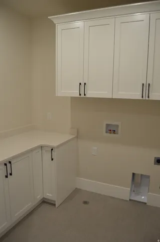 White shaker cabinetry with black hardware, light-toned countertop, and light-toned flooring