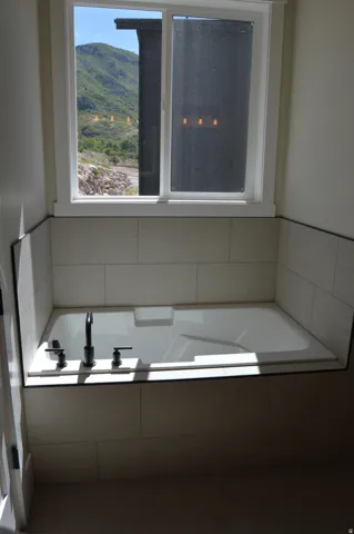 Built-in bathtub with matte black fixtures, surrounded by light-toned horizontal tile