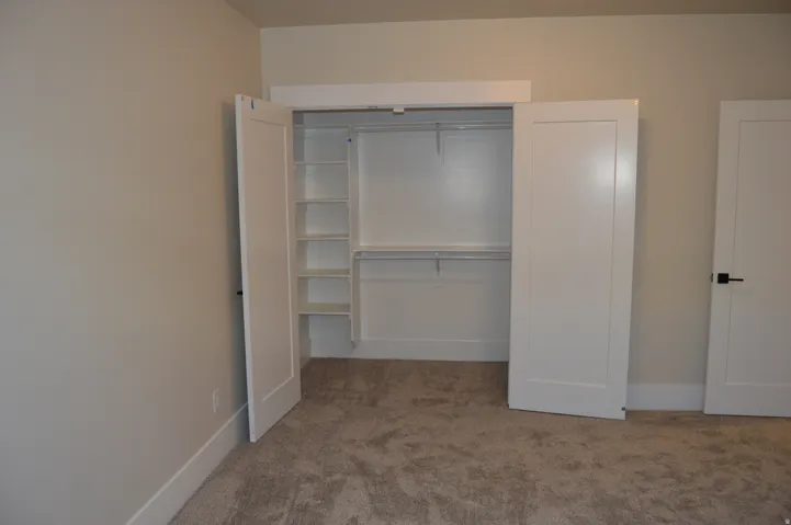 Closet featuring built-in shelving, hanging rods, and white bi-fold doors