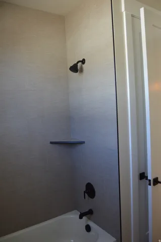Bathtub with tile surround, built-in corner shelf, and matte black fixtures