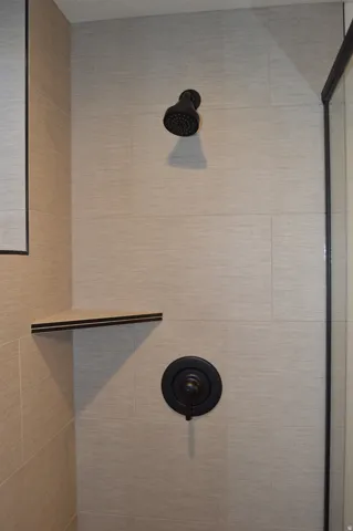 Textured tile shower surround with a matte black shower head and control