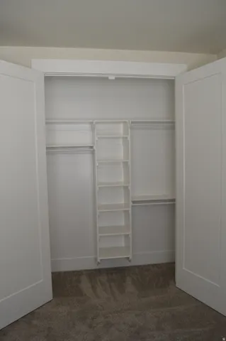Double bifold entry doors revealing a built-in closet system with multiple shelving units and clothing rods