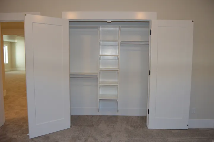 Double panel doors opening to a closet with built-in shelving and hanging rods
