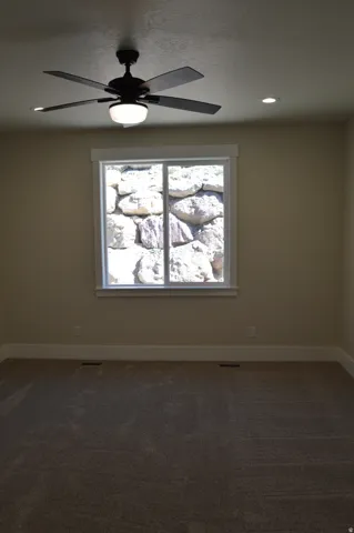 Ceiling fan with integrated lighting, recessed ceiling lighting, window with white trim, tan wall finish, and carpeted flooring
