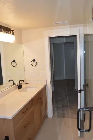 Wood-finish vanity with a single sink, light-toned countertop, and matte black faucet