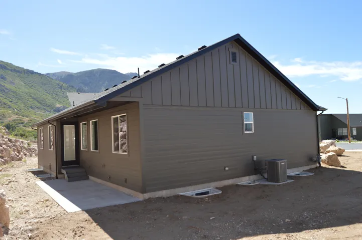 Exterior featuring horizontal siding, vertical siding, a dark roof, and multiple windows