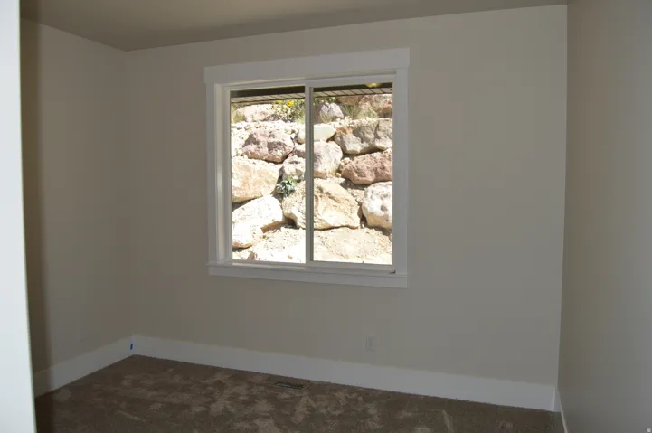 Neutral wall color, carpeted flooring, and a sliding window with white trim