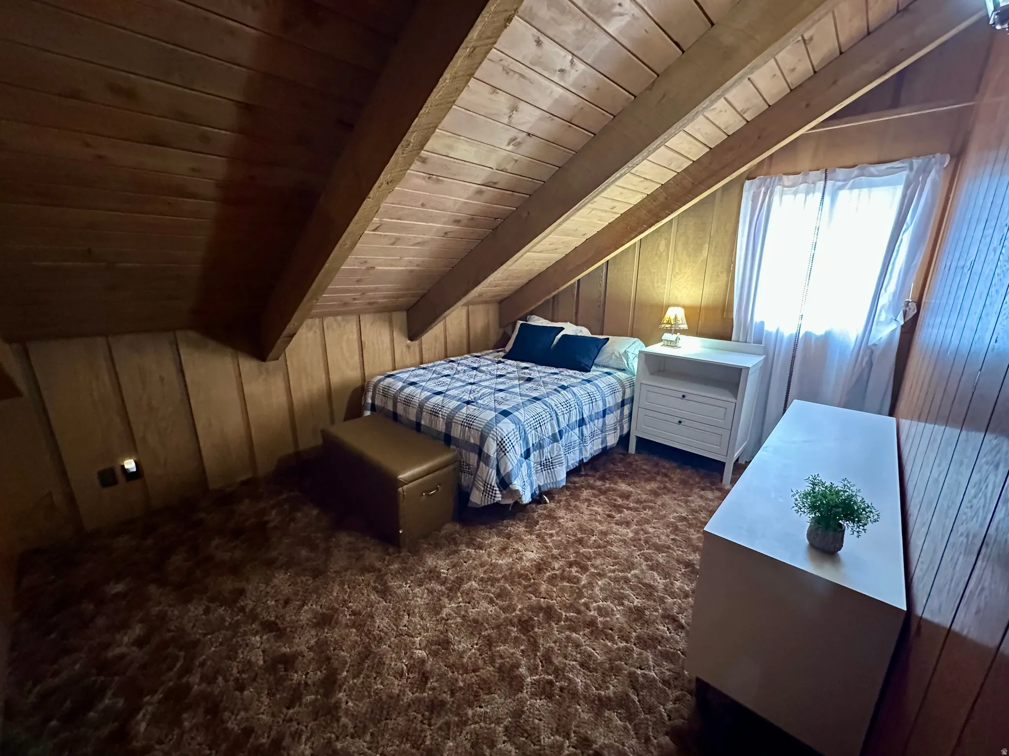 Bedroom featuring wooden walls, wood ceiling, lofted ceiling with beams, and dark carpet