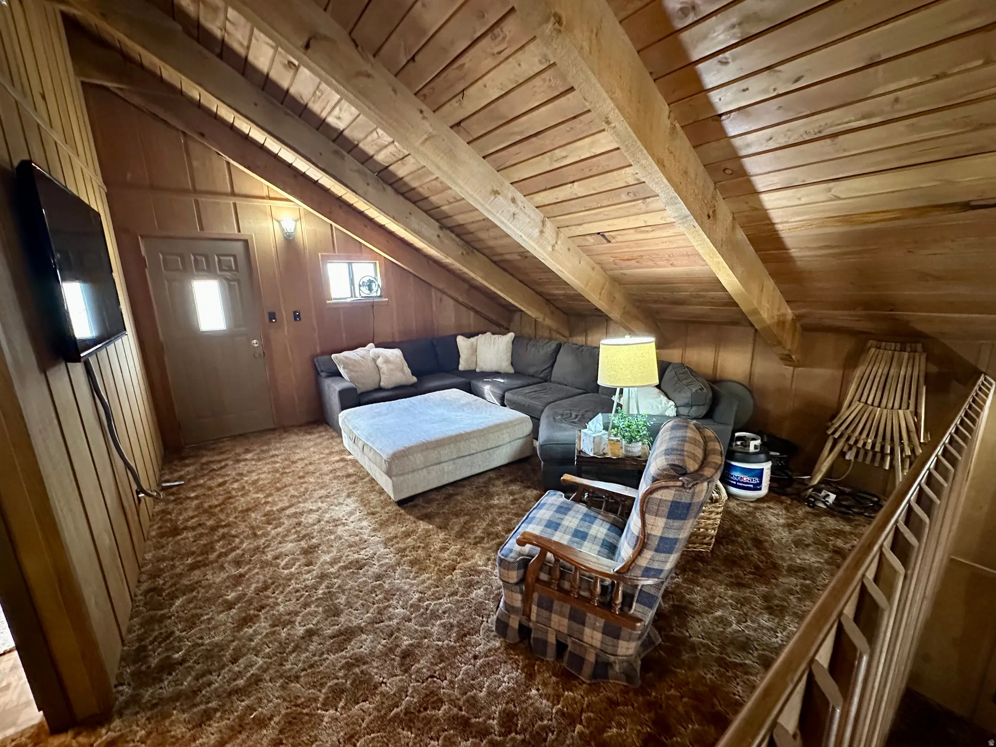 Sitting room with lofted ceiling with beams, wooden ceiling, wood walls, and carpet flooring