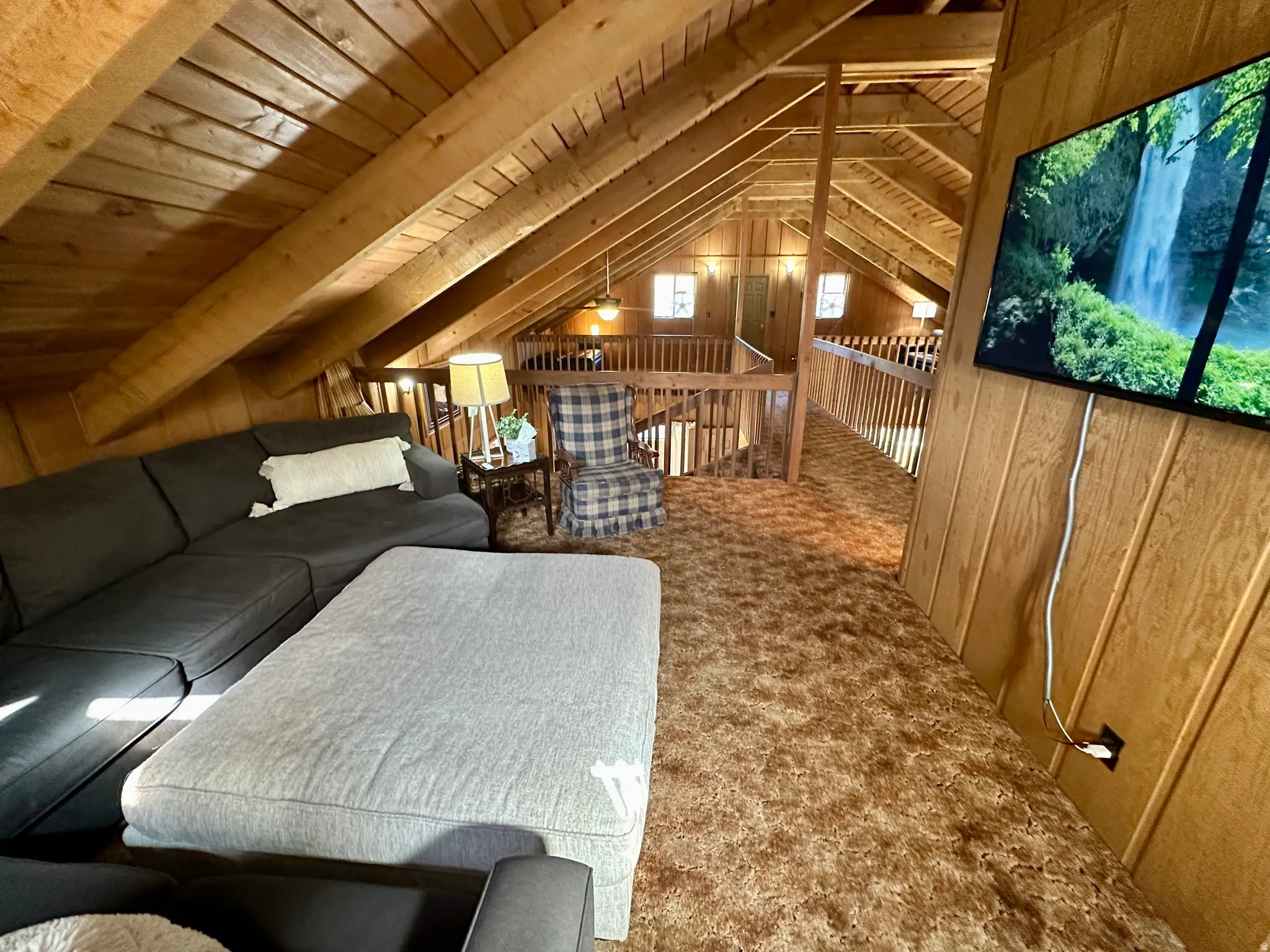 Living room with wood walls, carpet, and a wood ceiling with exposed beams