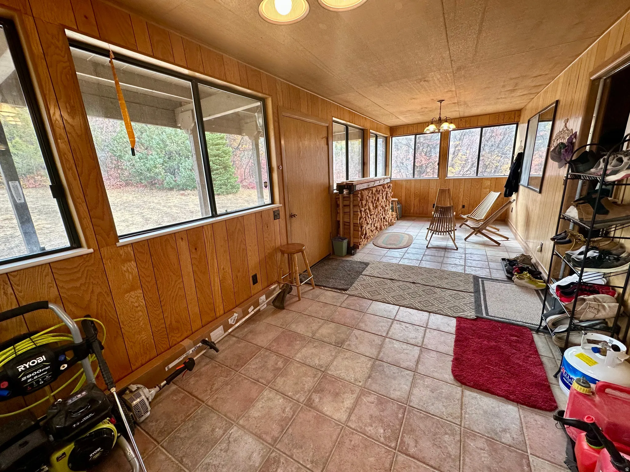 Sunroom / solarium with wooden walls, tile patterned floors, and suspended lighting