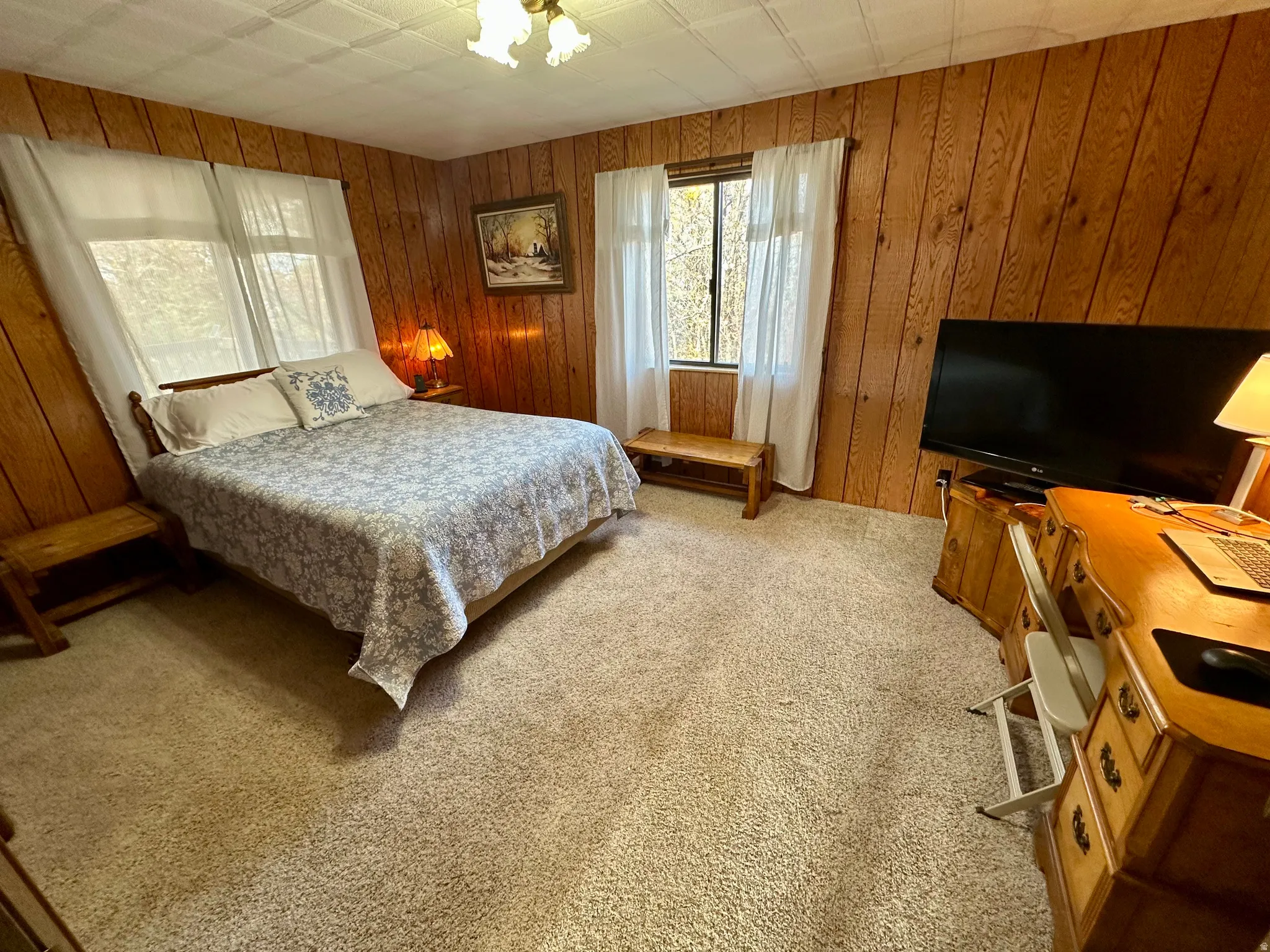Bedroom featuring light colored carpet and wood walls