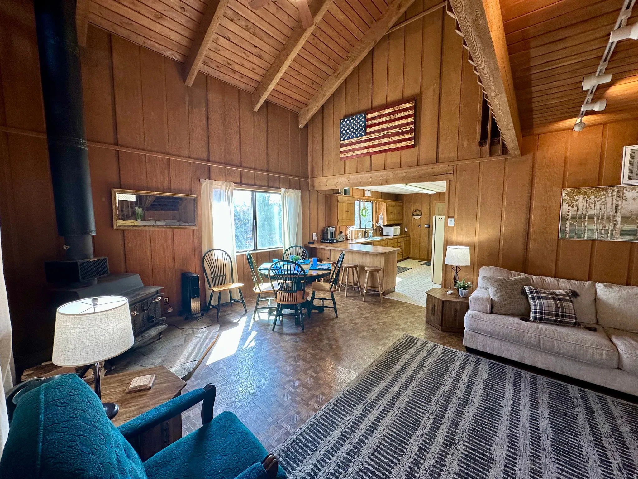 Living area featuring wood walls, a high wooden beamed ceiling, wood finished floors, and a wood stove