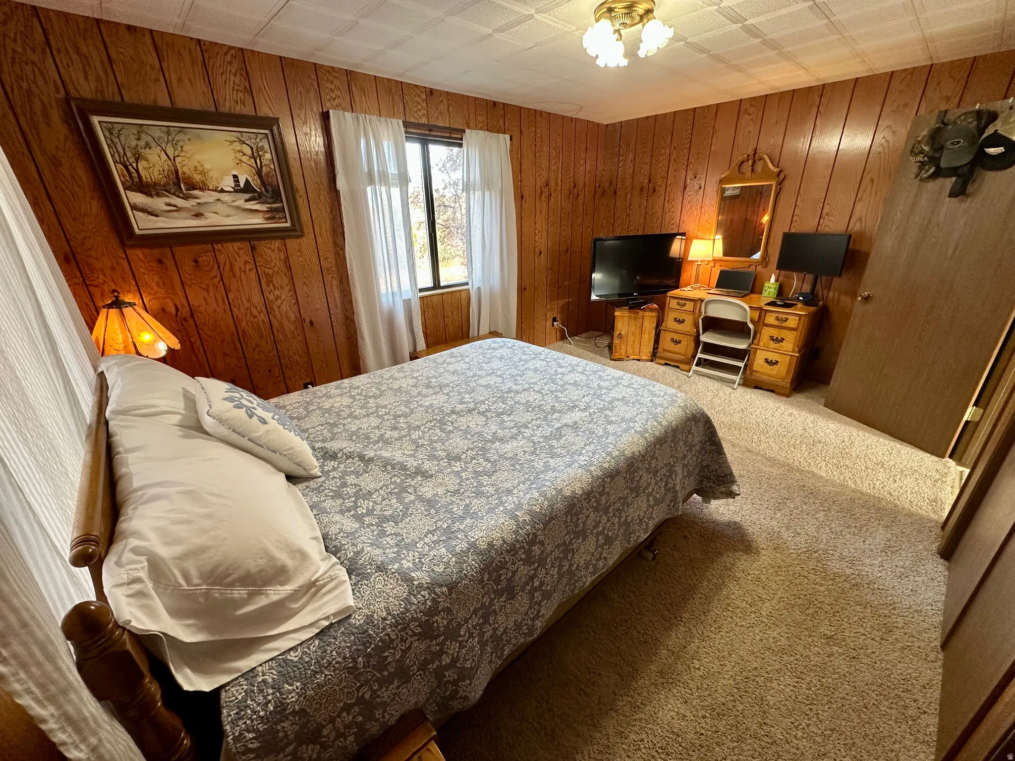 Bedroom featuring light colored carpet and wooden walls