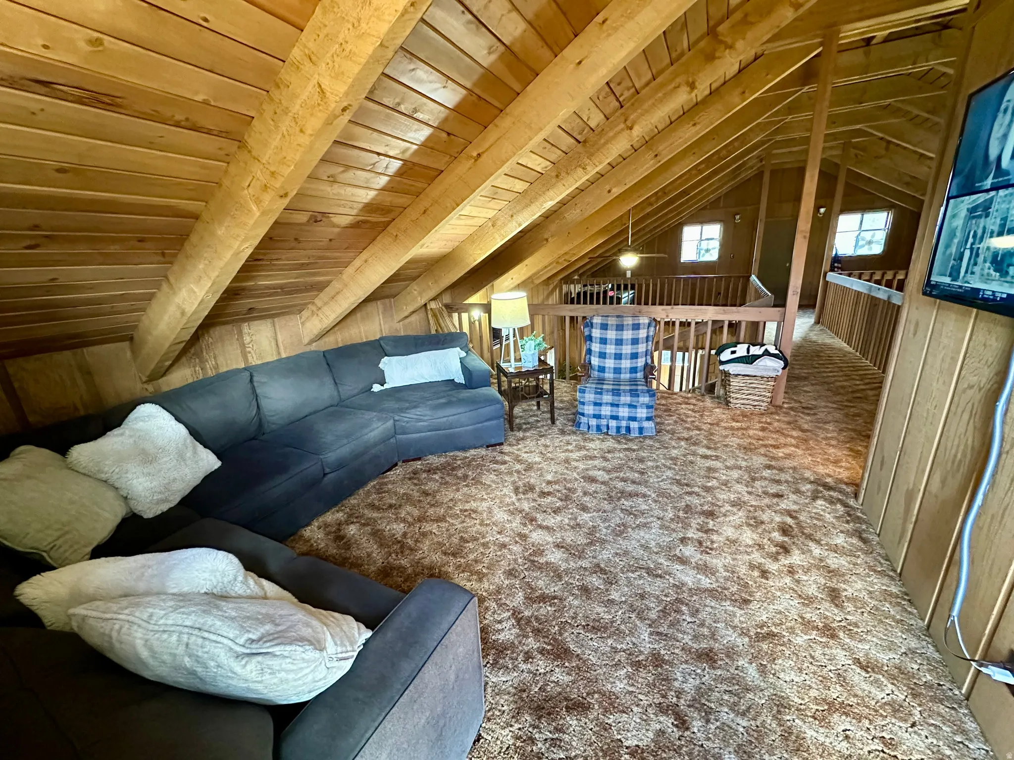 Carpeted living area featuring lofted ceiling with beams, wood ceiling, and wooden walls