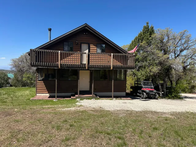View of front of property featuring a front lawn, a balcony, and a wooden deck