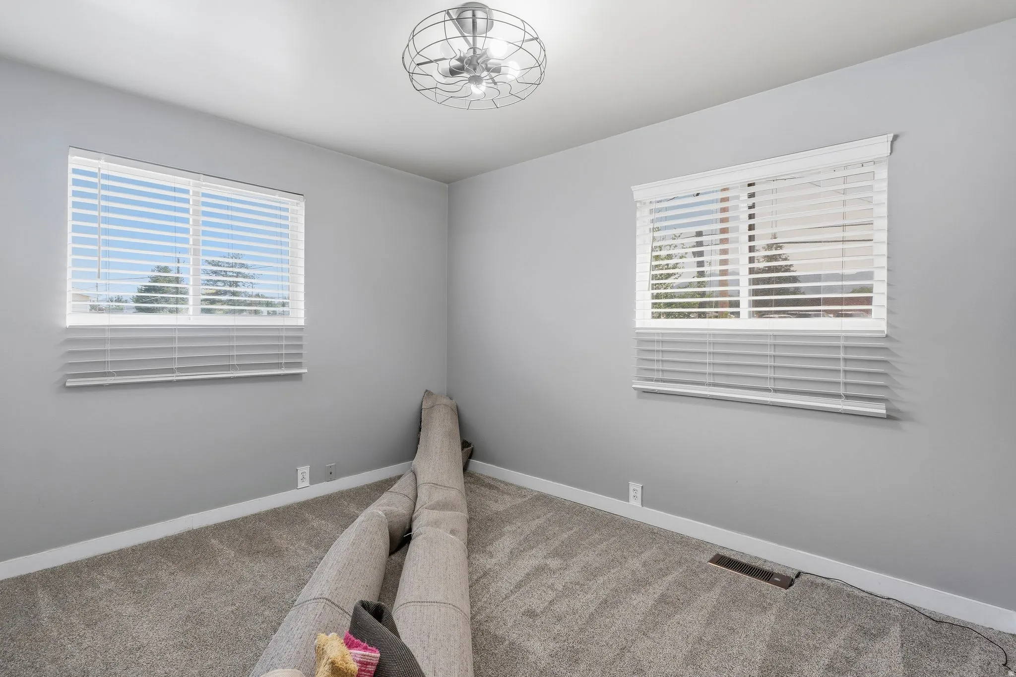Room featuring two windows with white blinds, gray wall paint, and gray carpet flooring