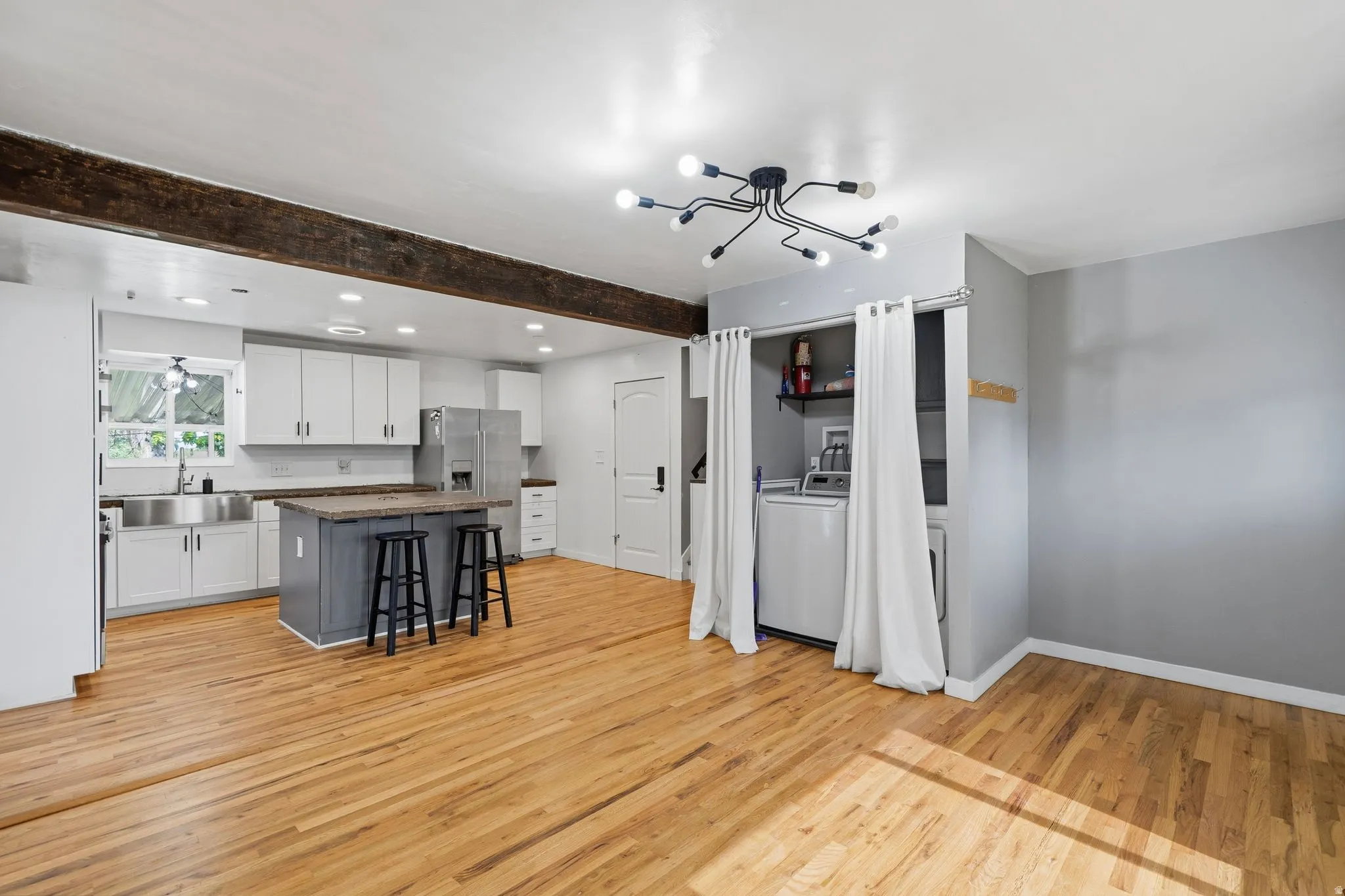 Open-concept kitchen with white cabinetry, stainless steel appliances, and a central island with bar seating