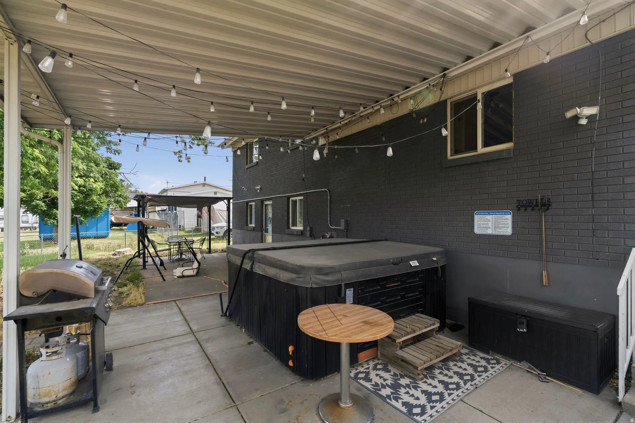 Covered patio featuring string lighting, concrete flooring, and an included hot tub
