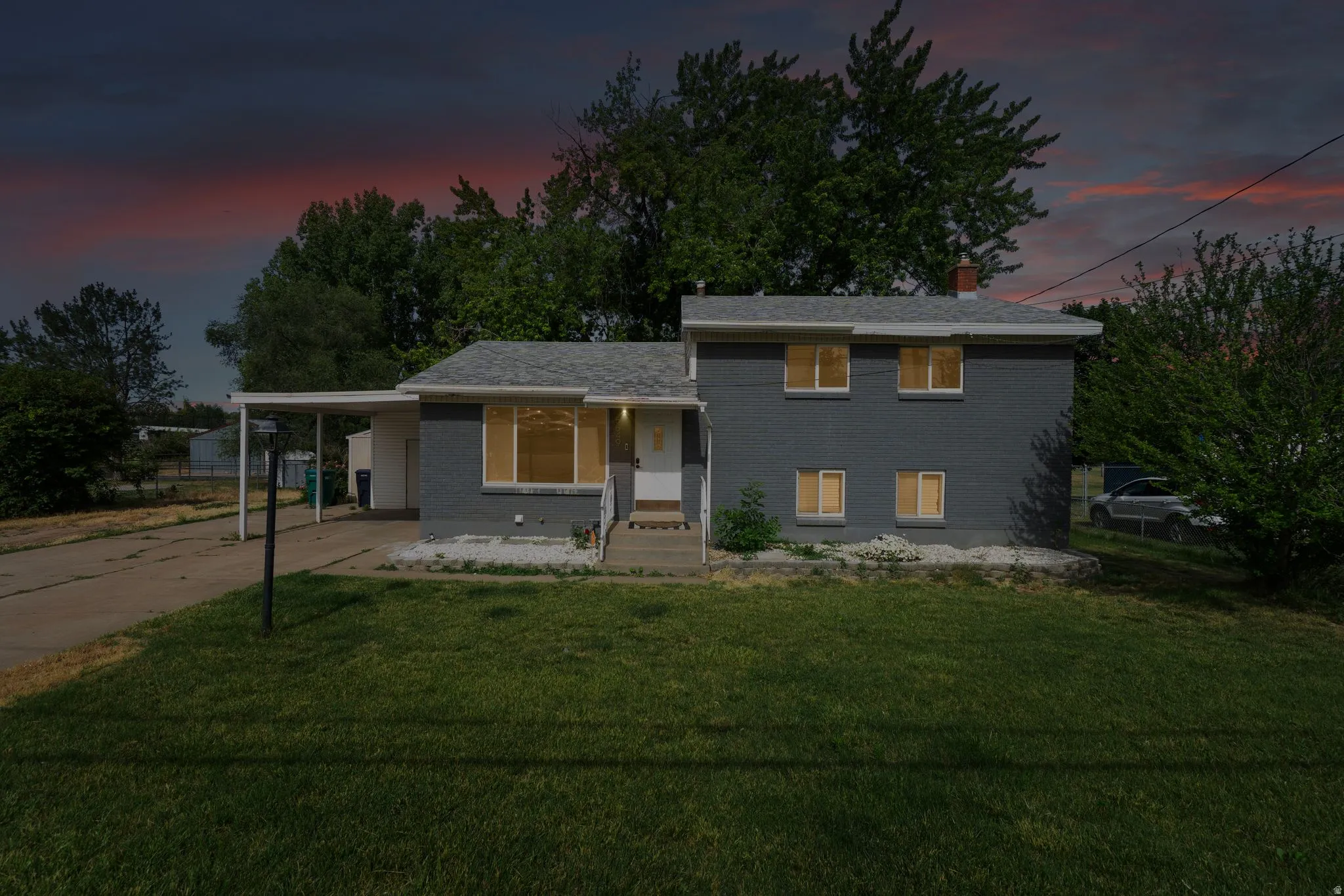Split-level residence featuring a gray exterior and a white front door