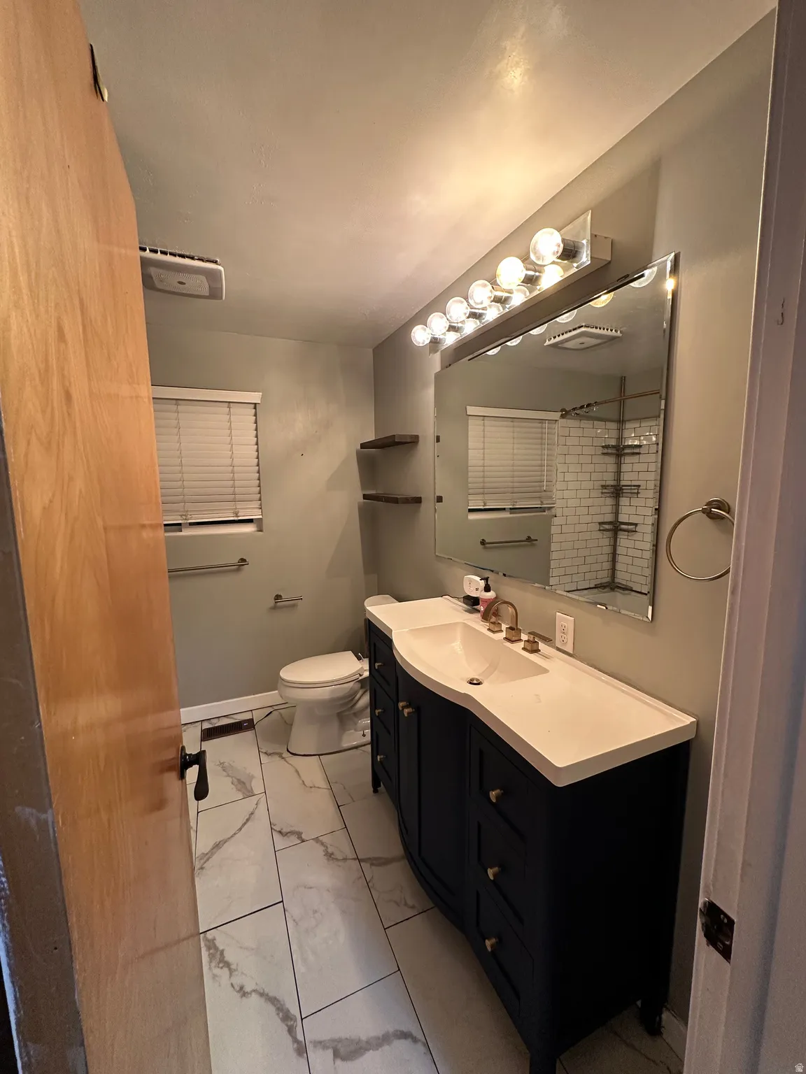 Bathroom with light marble finish flooring, vanity, and a shower