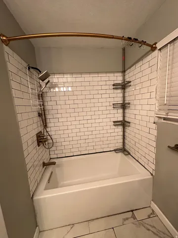 Full bath with shower / bathtub combination and a textured ceiling