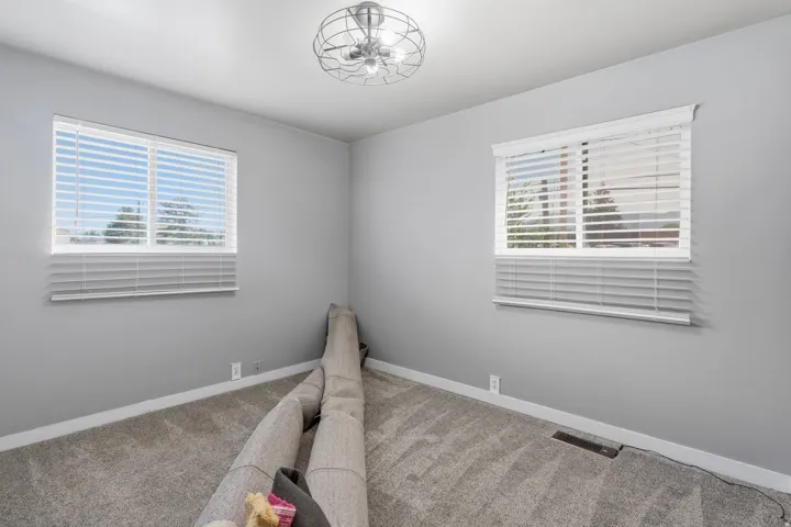 Room featuring two windows with white blinds, gray wall paint, and gray carpet flooring