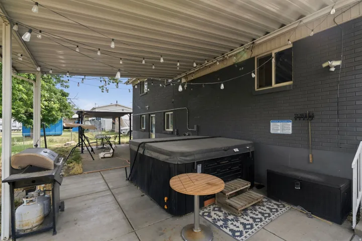 Covered patio featuring string lighting, concrete flooring, and an included hot tub