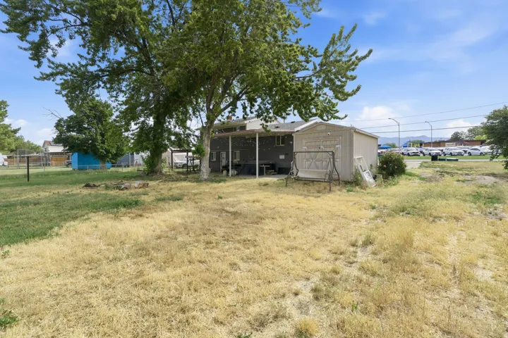 Expansive rear yard featuring mature trees and a detached storage shed