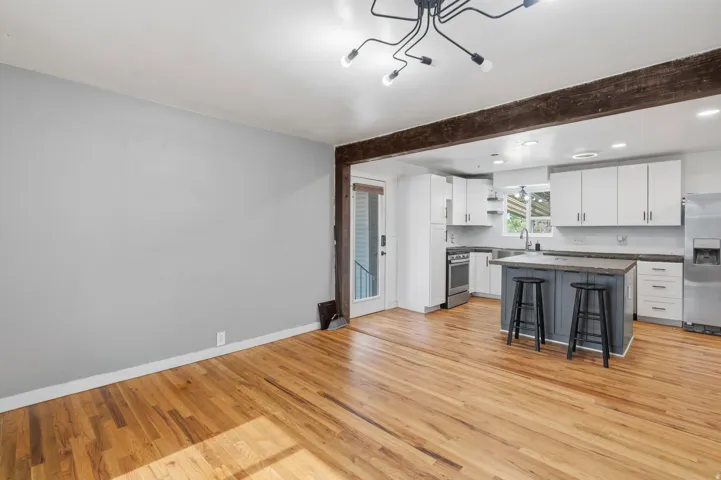 Expansive kitchen featuring white cabinetry, stainless steel appliances, a center island with seating, and dark countertops