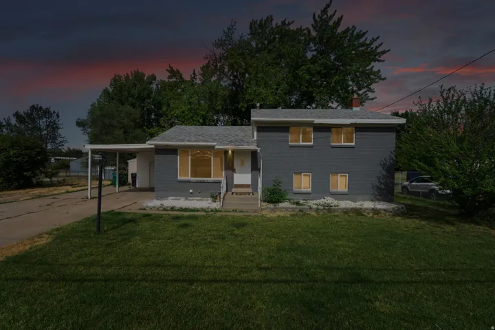 Split-level residence featuring a gray exterior and a white front door
