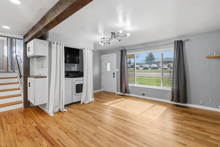 Spacious room featuring wood-finish flooring, a contemporary light fixture, and a large front window