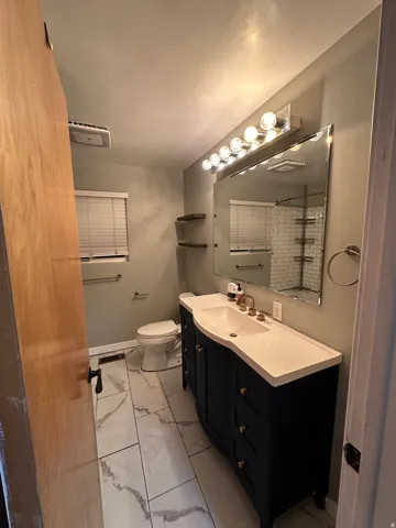Bathroom with light marble finish flooring, vanity, and a shower