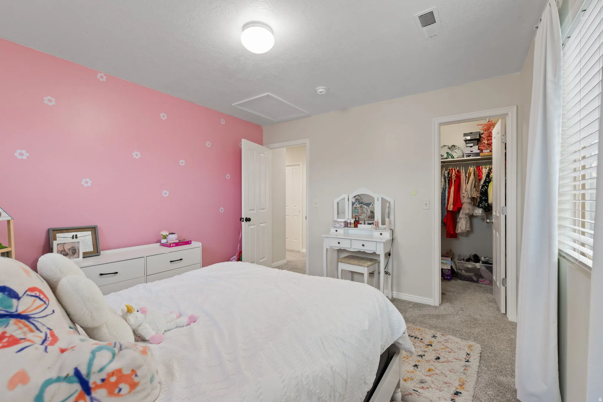 Bedroom with light carpet, a spacious closet, and an accent wall