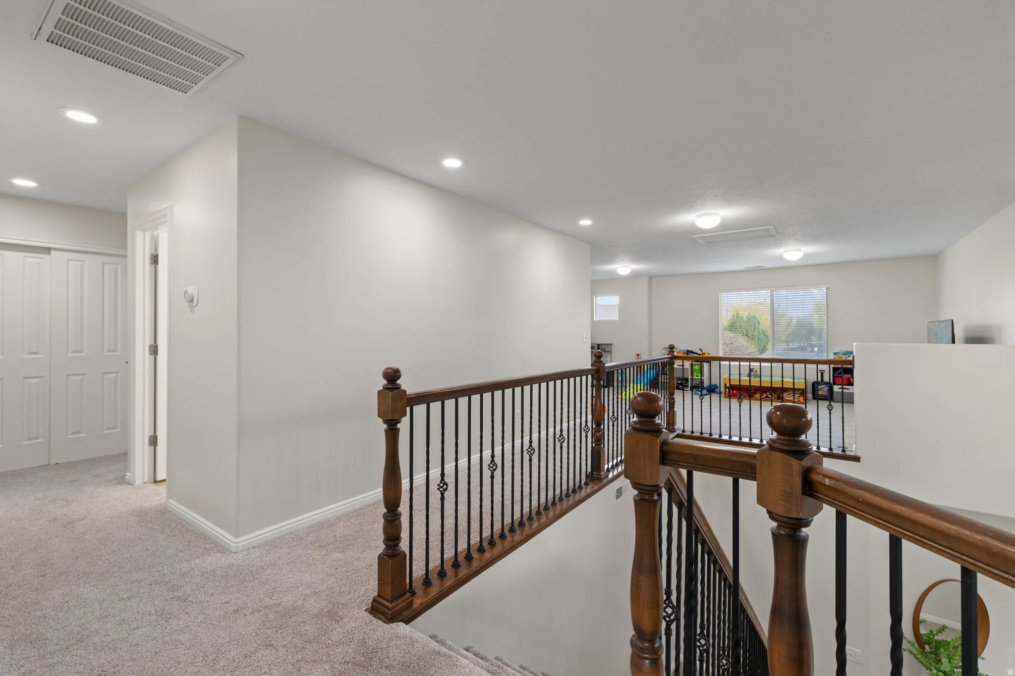 Hallway with an upstairs landing, carpet flooring, and recessed lighting