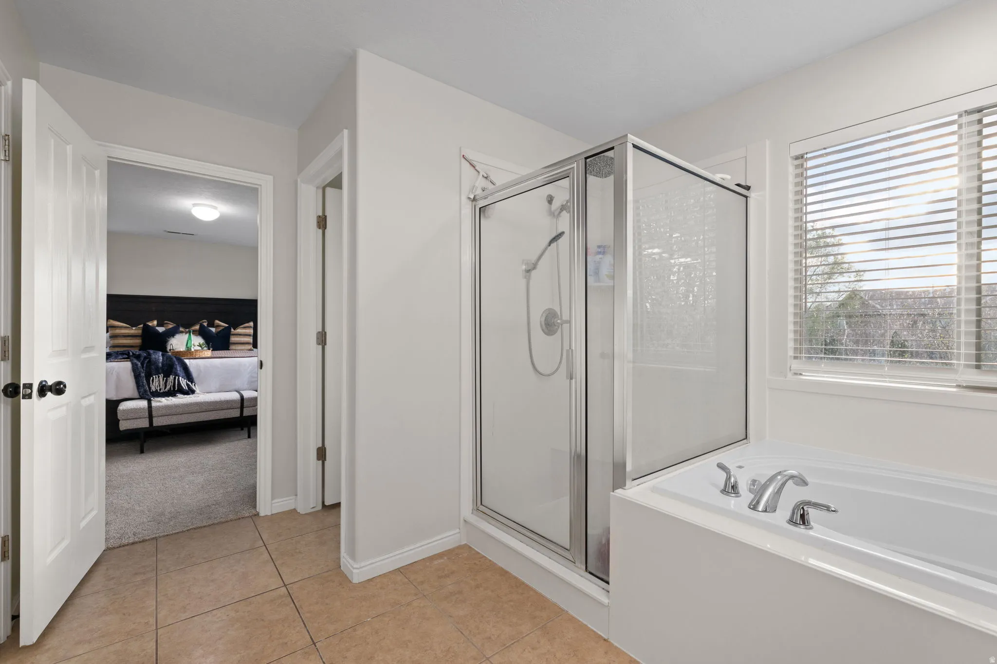 Ensuite bathroom with a shower stall, light tile patterned floors, a bath, and light colored carpet