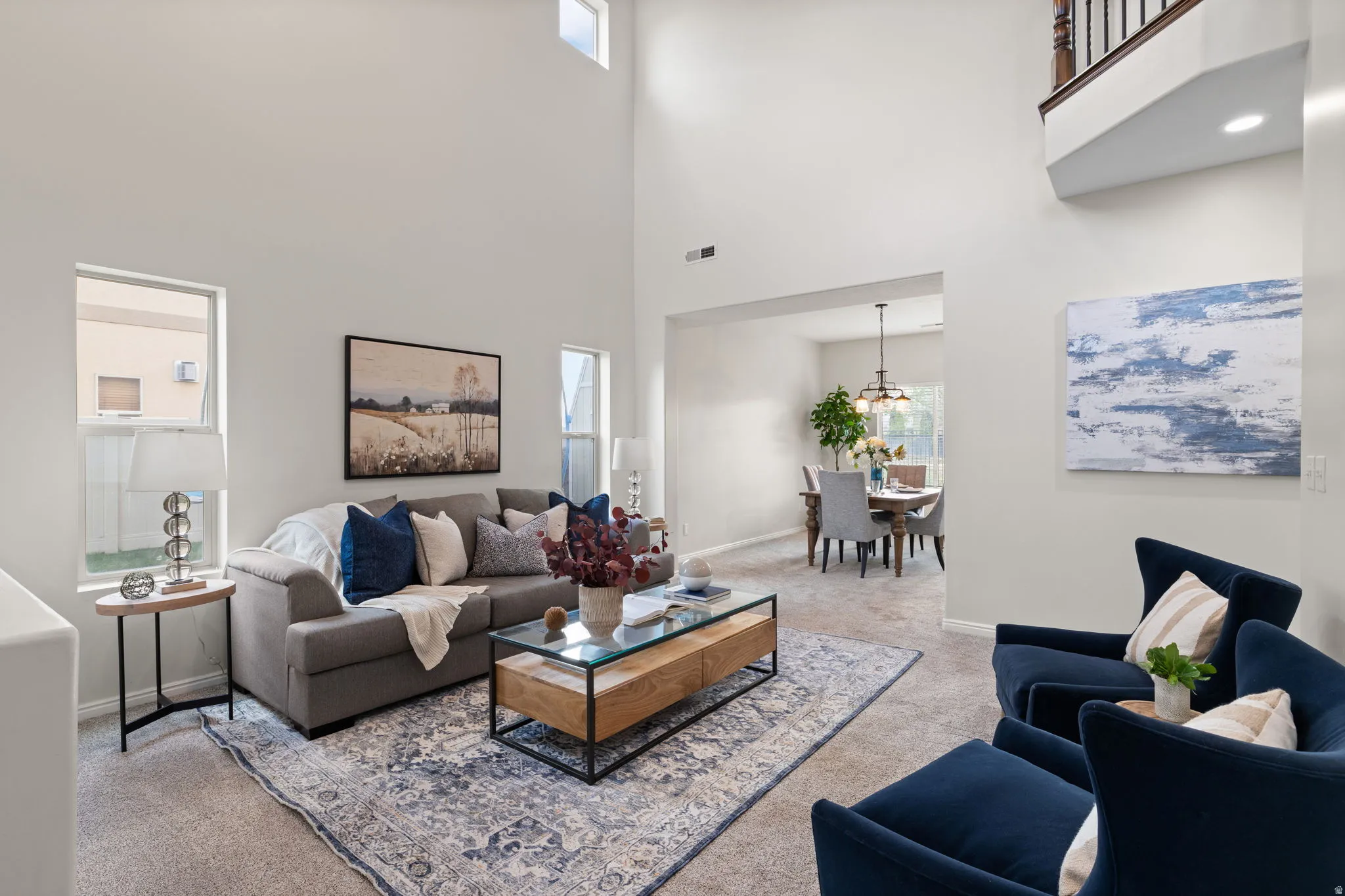 Living area featuring light carpet, a high ceiling, and a chandelier