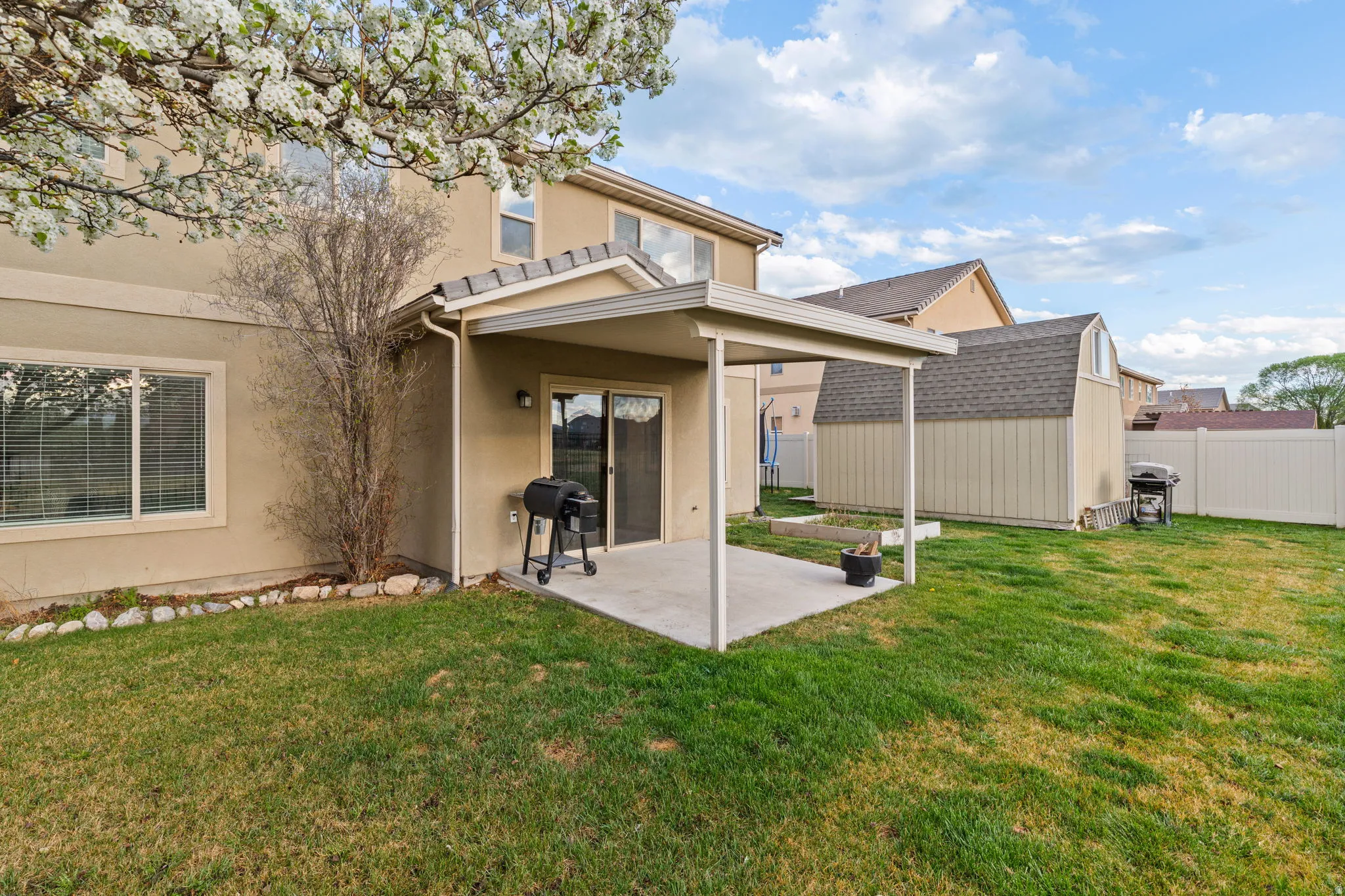 Rear view of property with a patio, stucco siding, and a storage unit