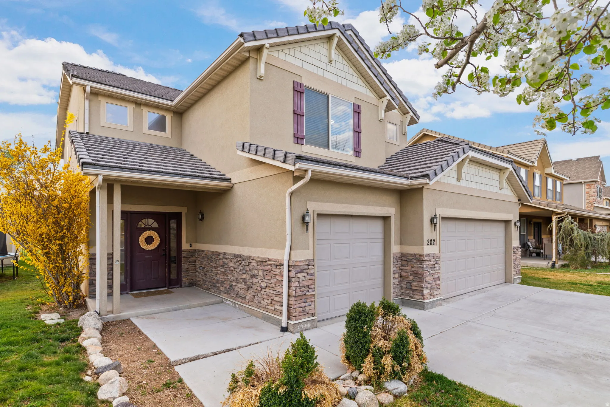 View of front of property featuring stucco siding, stone siding, driveway, and a garage