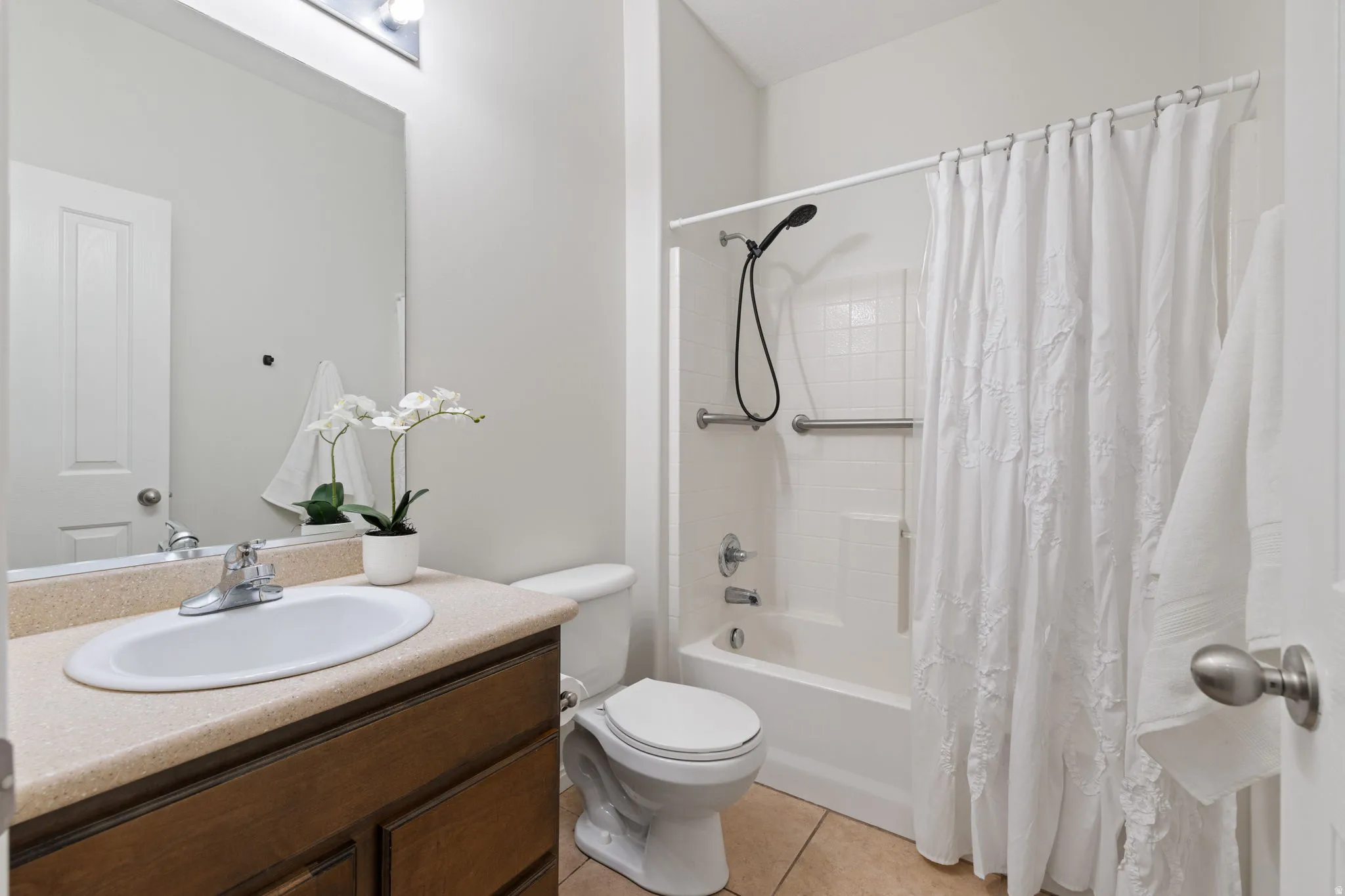 Full bath with vanity, shower / bath combination with curtain, and light tile patterned floors