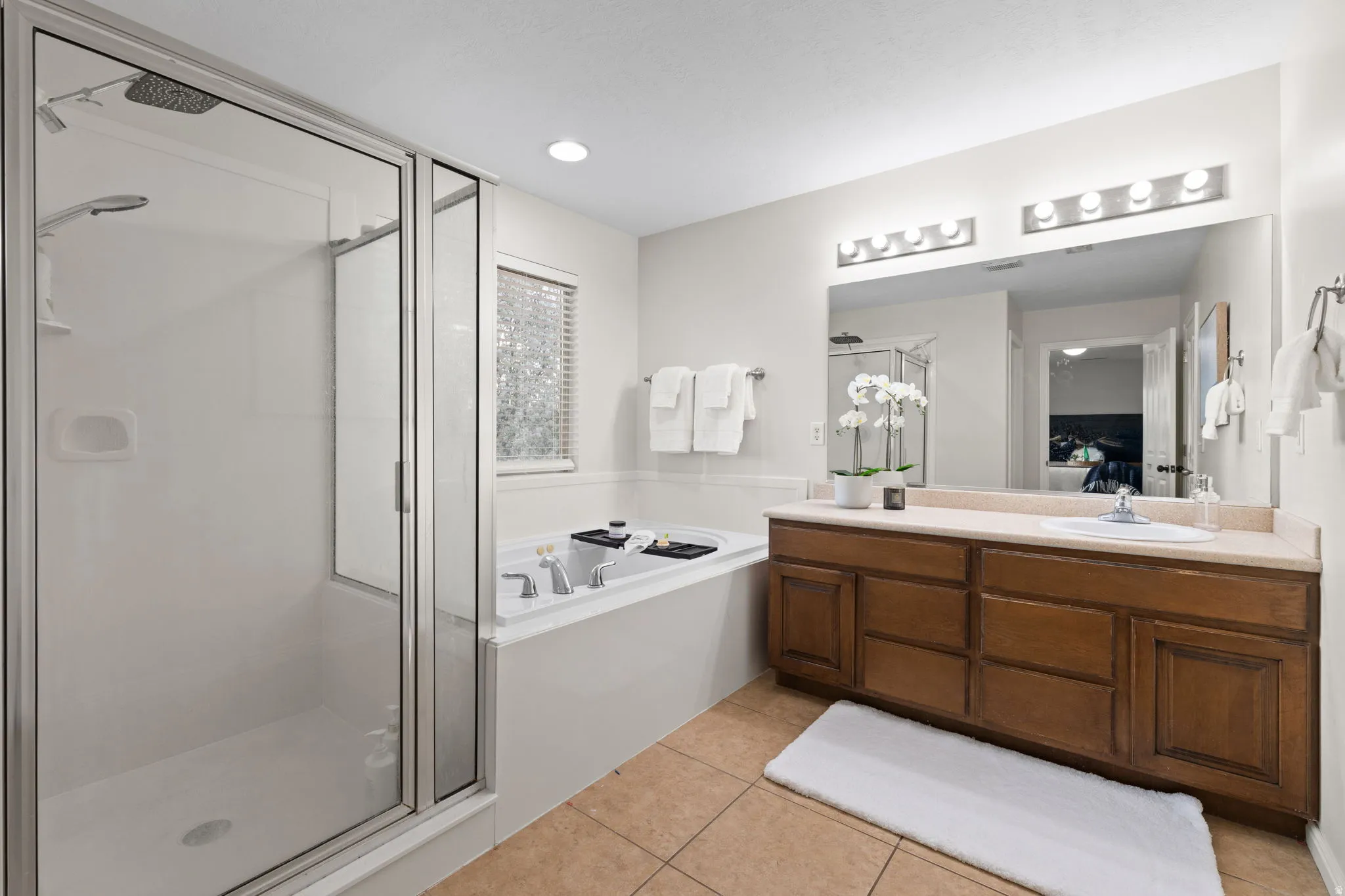 Ensuite bathroom with vanity, a garden tub, a shower stall, and light tile patterned flooring