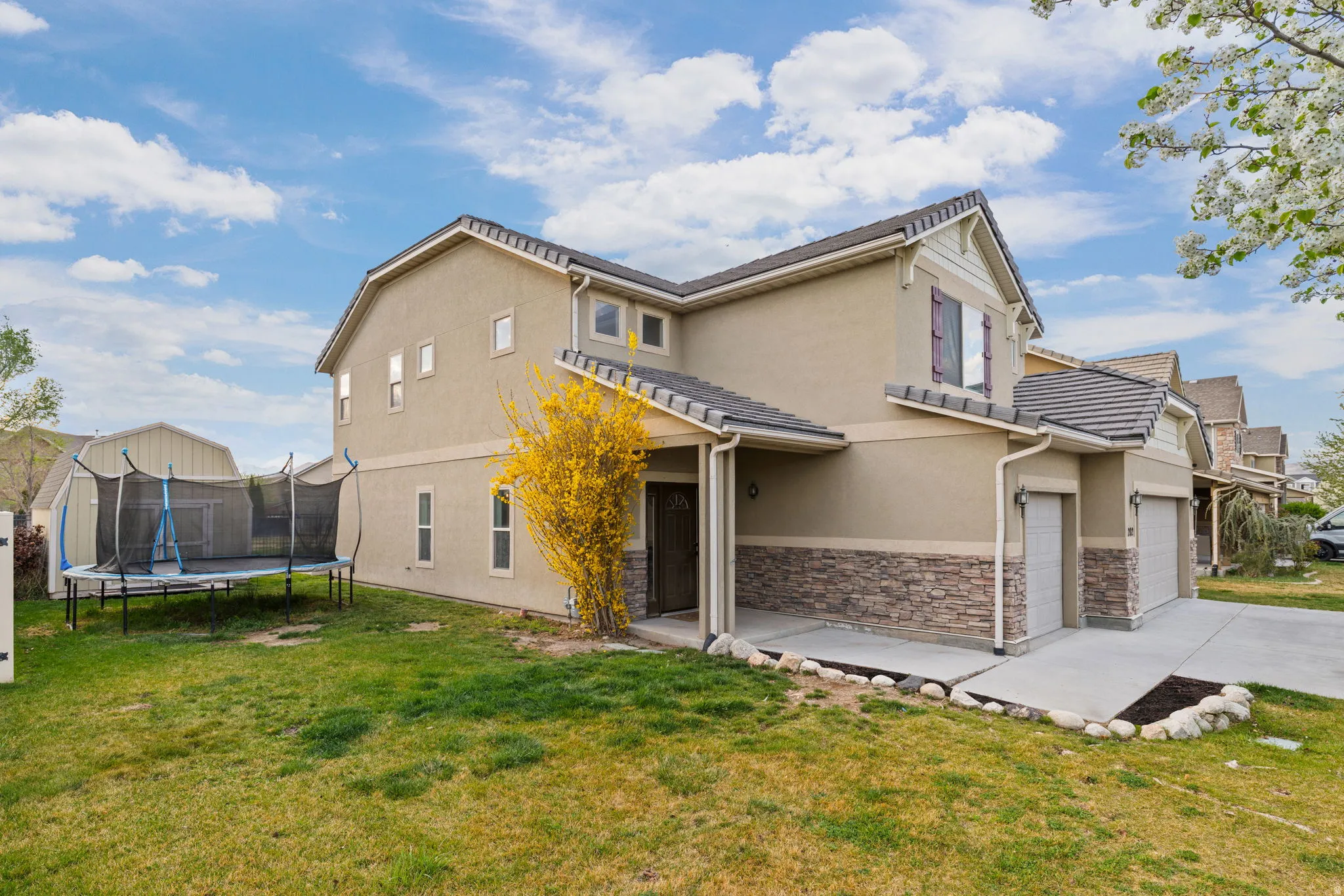 Two-story stucco home featuring a stone veneer accent