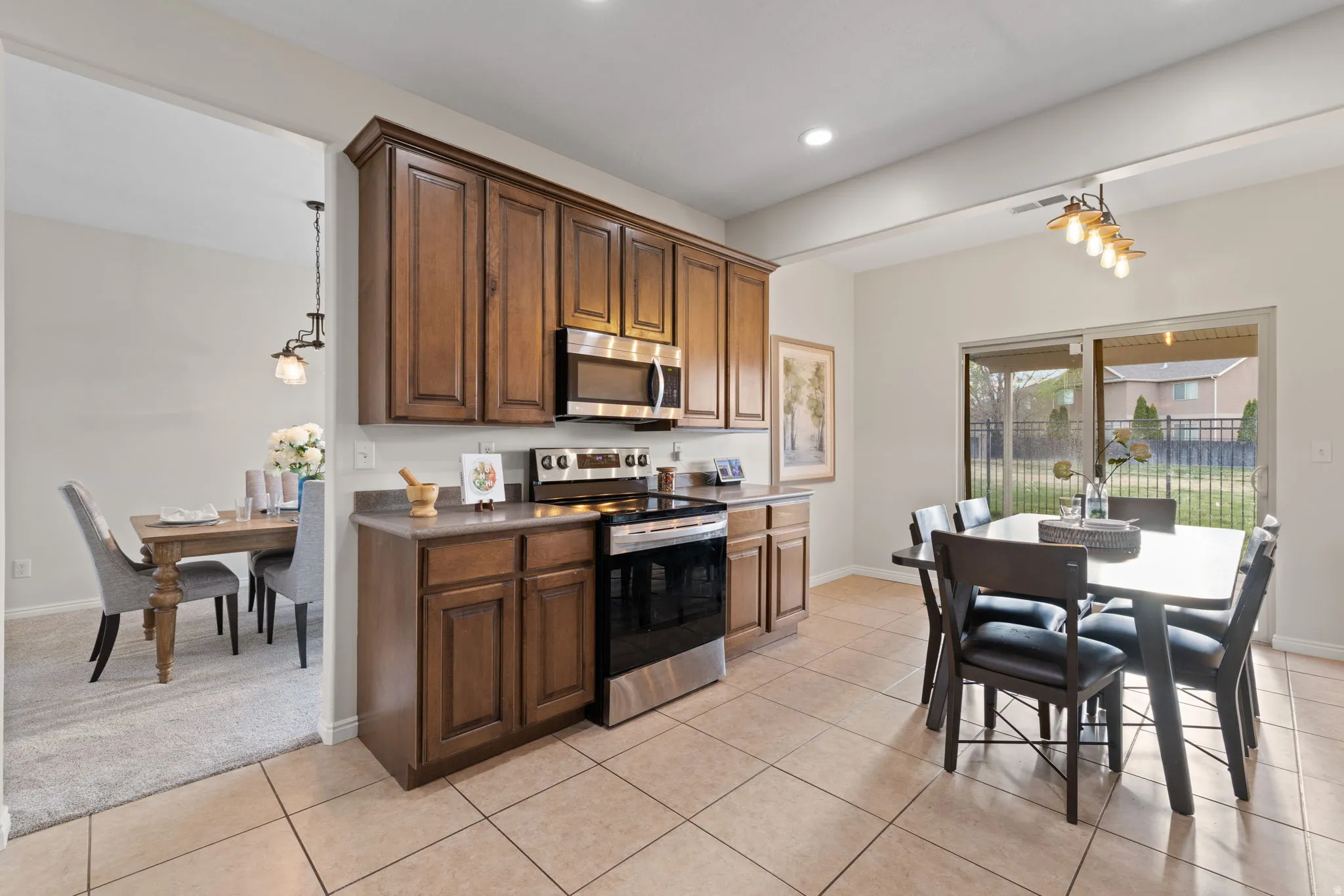 Kitchen featuring stainless steel appliances, pendant lighting, dark countertops, and light tile patterned floors