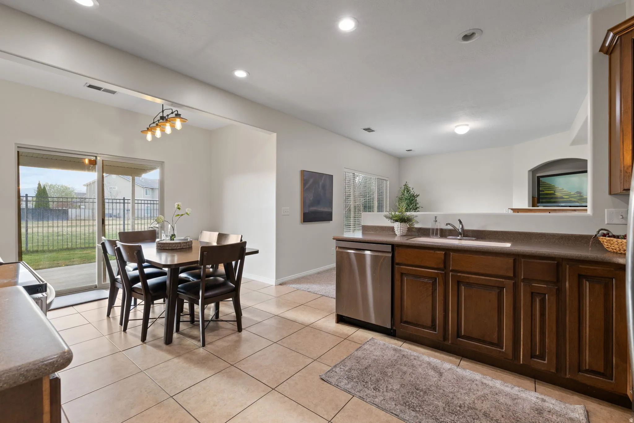 Kitchen featuring dark countertops, stainless steel appliances, light tile patterned flooring, and dark wood finish cabinetry