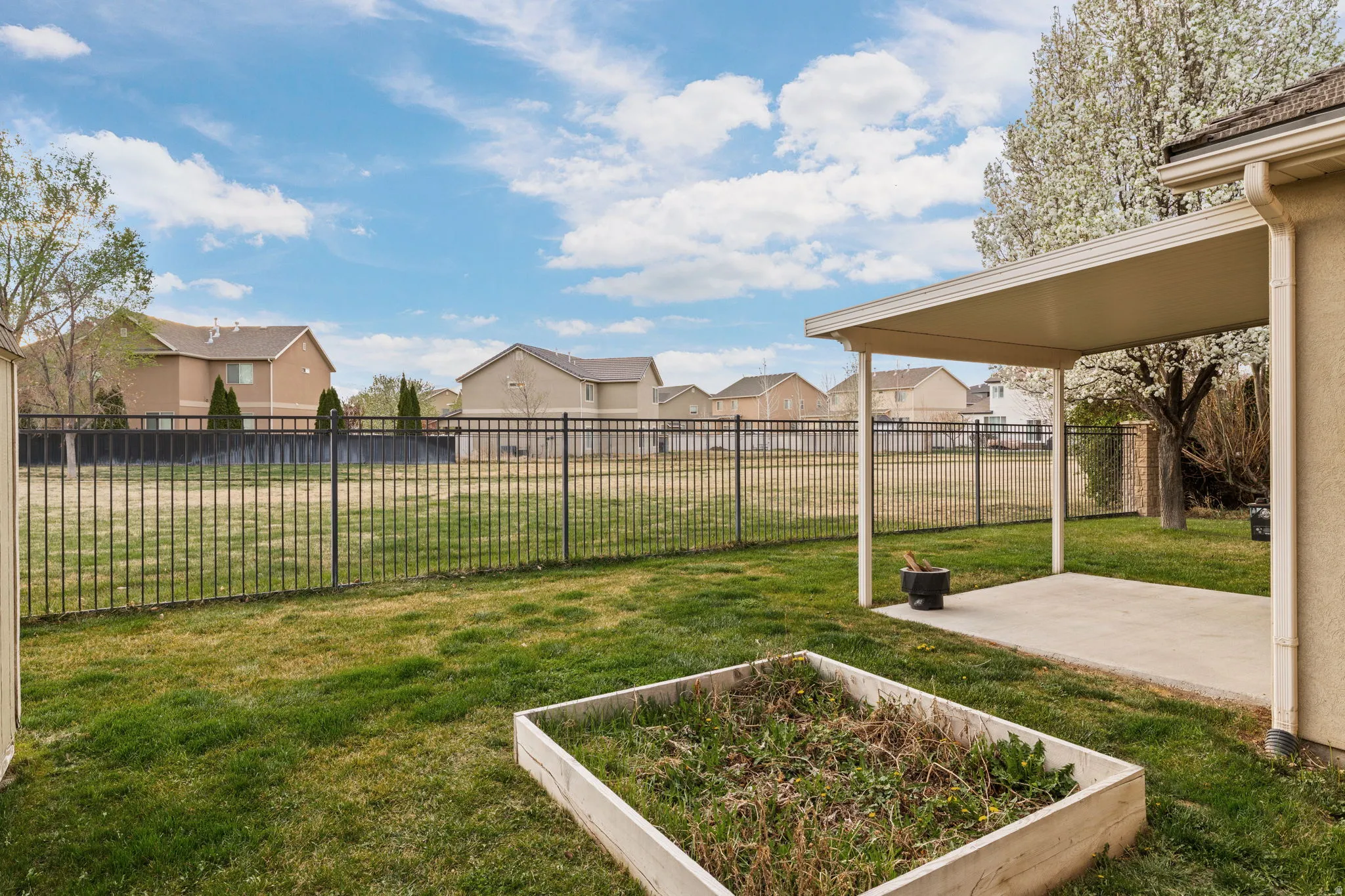 Fenced backyard featuring a residential view, a patio, and a garden