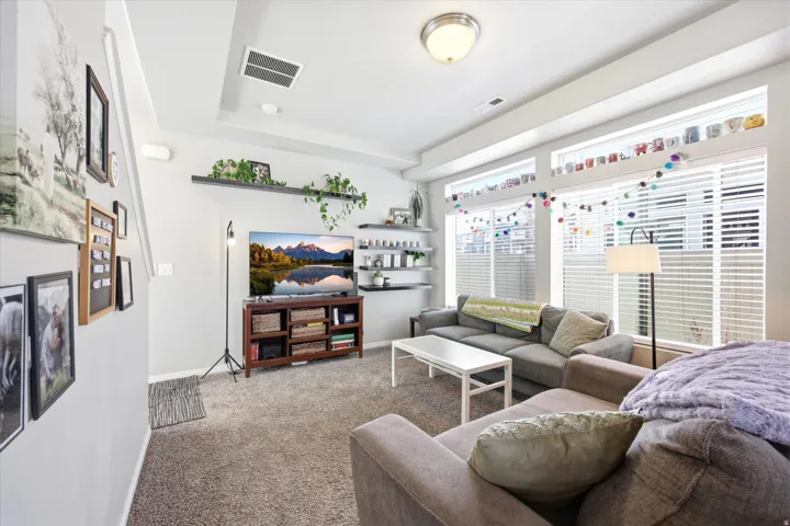 Carpeted living area featuring baseboards and a tray ceiling