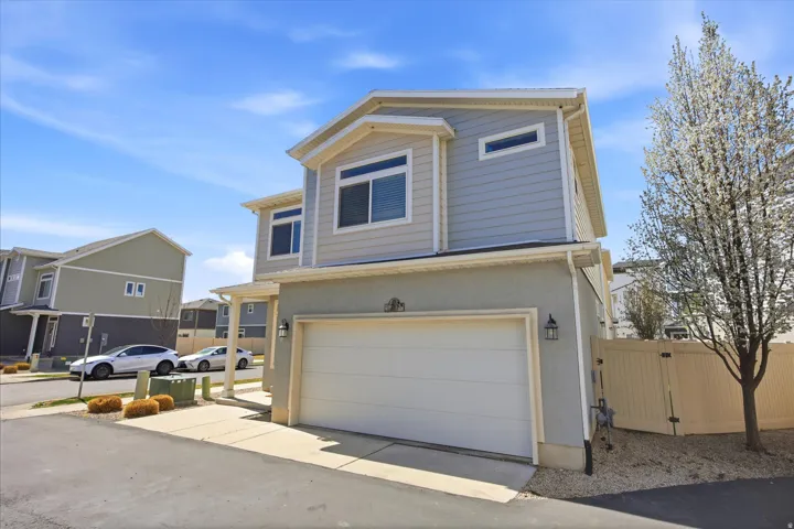 View of front of property with a gate, an attached garage, and stucco siding