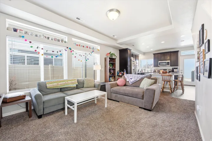 Living area with light carpet and recessed lighting