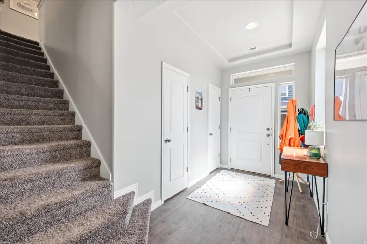 Foyer with wood finished floors and a raised ceiling