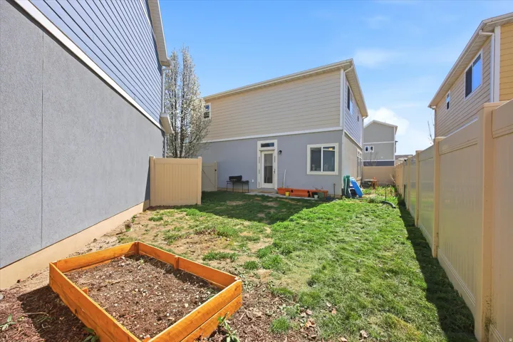 Back of house with a vegetable garden and a fenced backyard